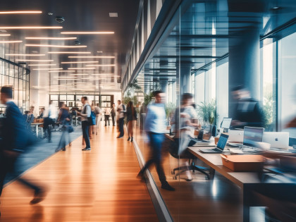 Bewegte Szene in einem modernen Büro, Menschen laufen und arbeitem am Schreibtisch. Bild für Onlinevortrag "Sucht am Arbeitsplatz" 