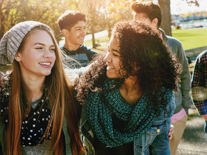 Teenager unterschiedlicher Ethnien und Geschlechts lächeln in die Kamera. BIld für den Vortrag "Grundlagen Sucht in Kindheit und Jugendalter" 